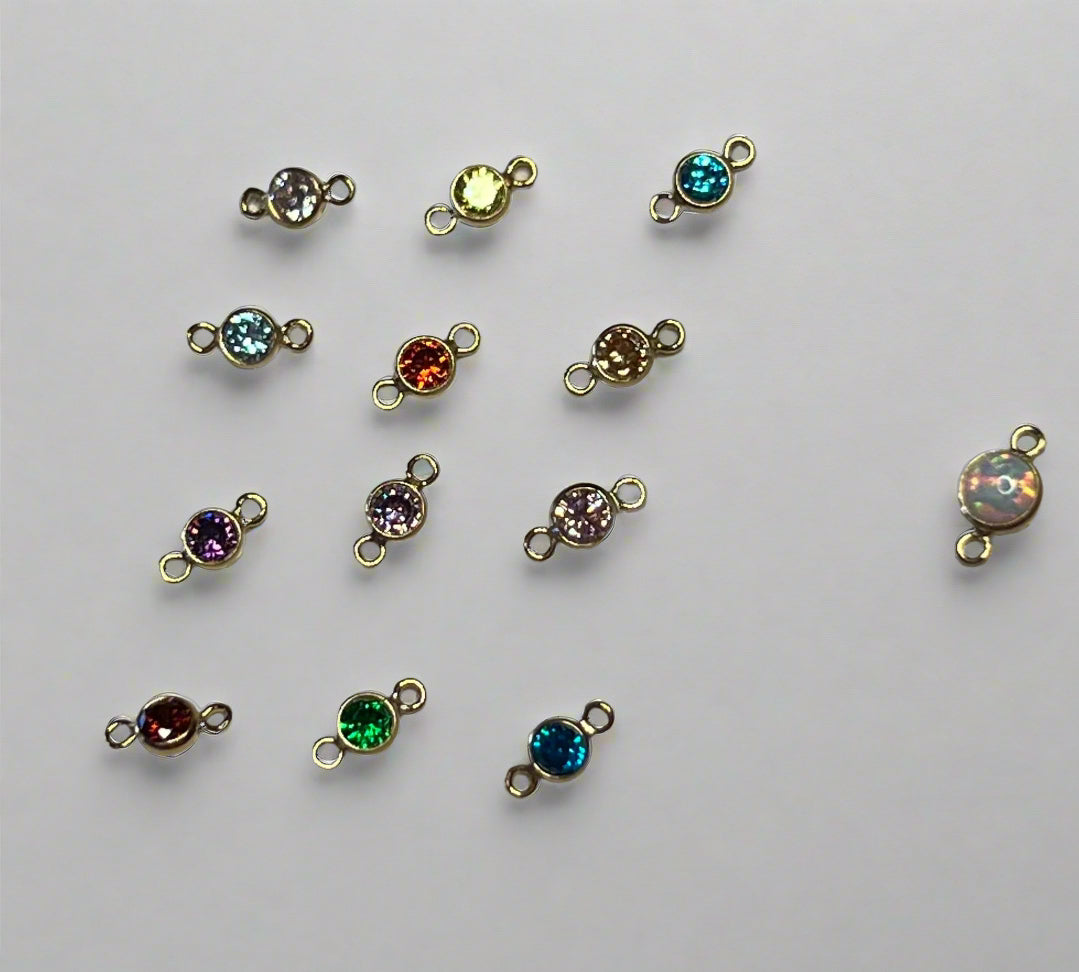 Set of small jewelry connectors with colored gemstones on a gray background