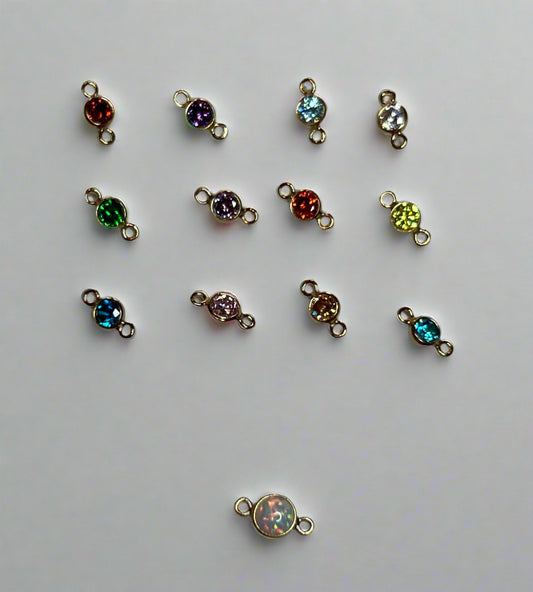 Goldfillred jewelry connectors with colored gemstones on a light gray surface